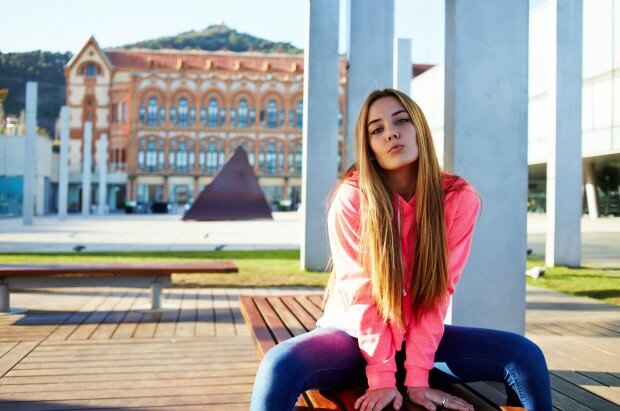 Portrait of a young girl student sitting on a bench near the Uni