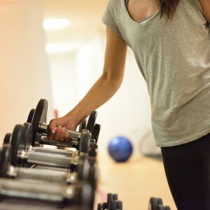 Gym woman strength training lifting dumbbell weights getting rea